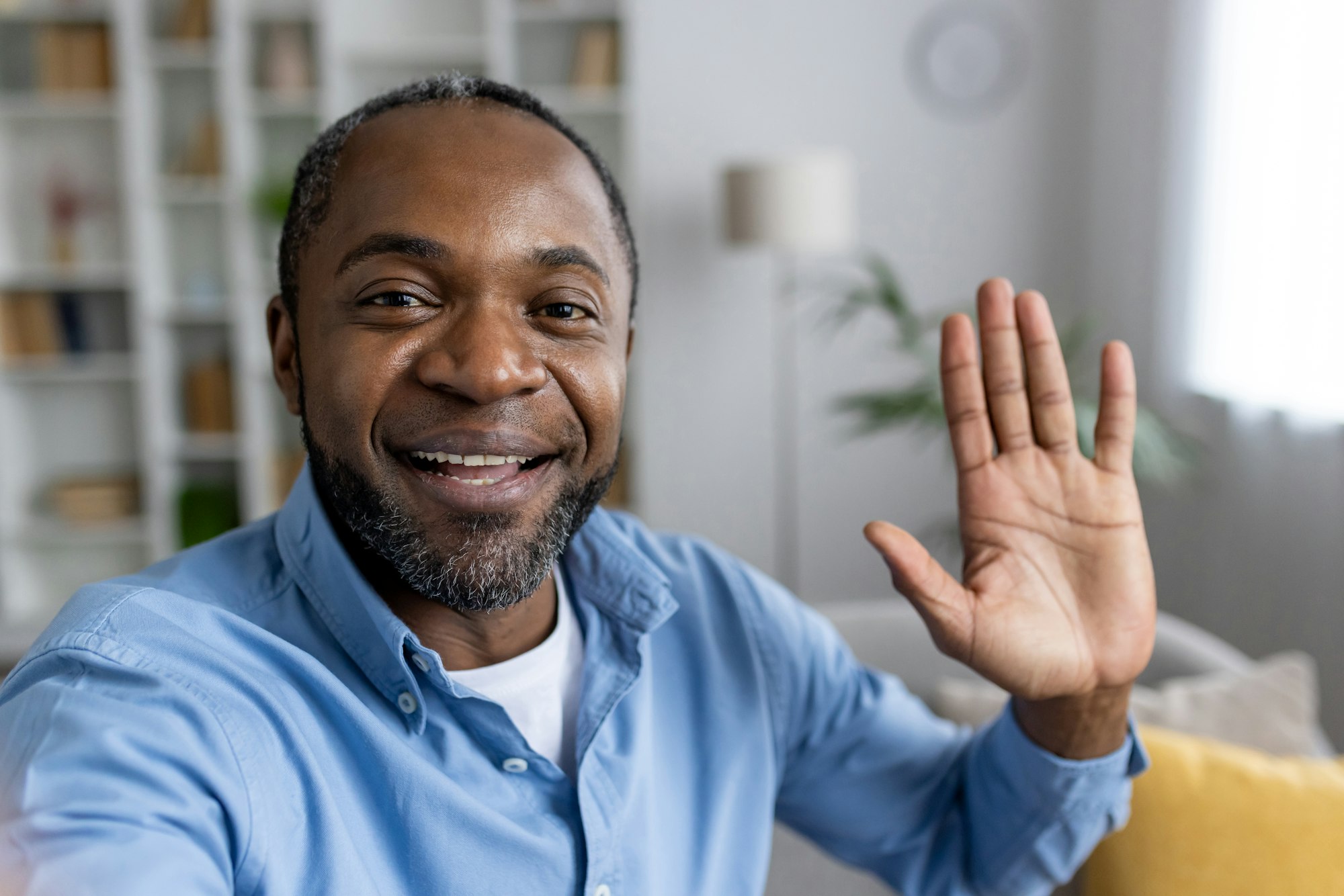 Front person view of african american man in shirt waving hello while starting video call in